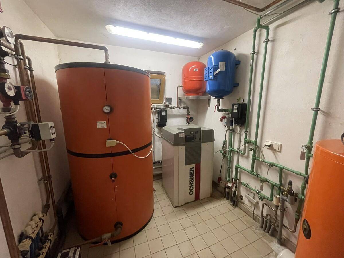 Heizungsraum mit großem Warmwasserspeicher und moderner Wärmepumpe.