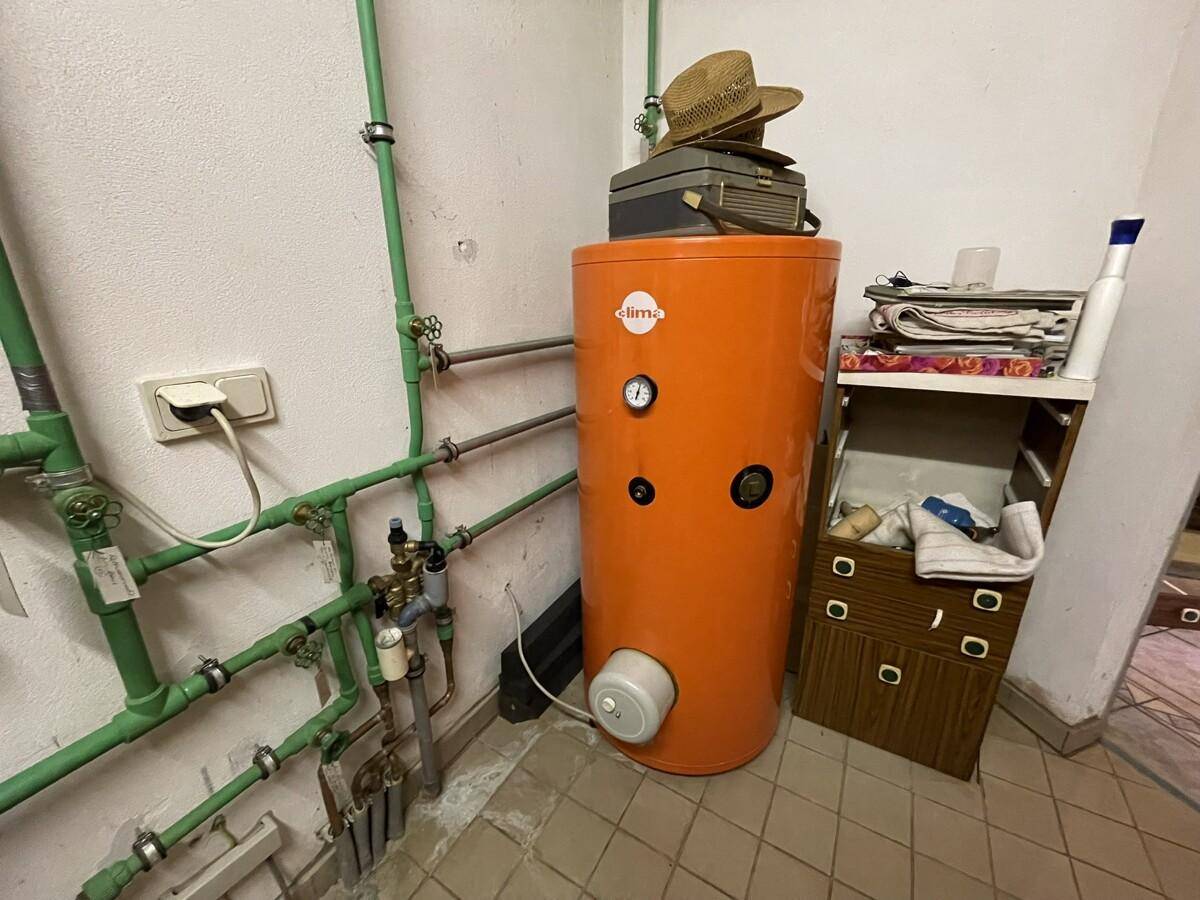 Detailansicht des Warmwasserspeichers und der Rohrleitungen im Heizungsraum.