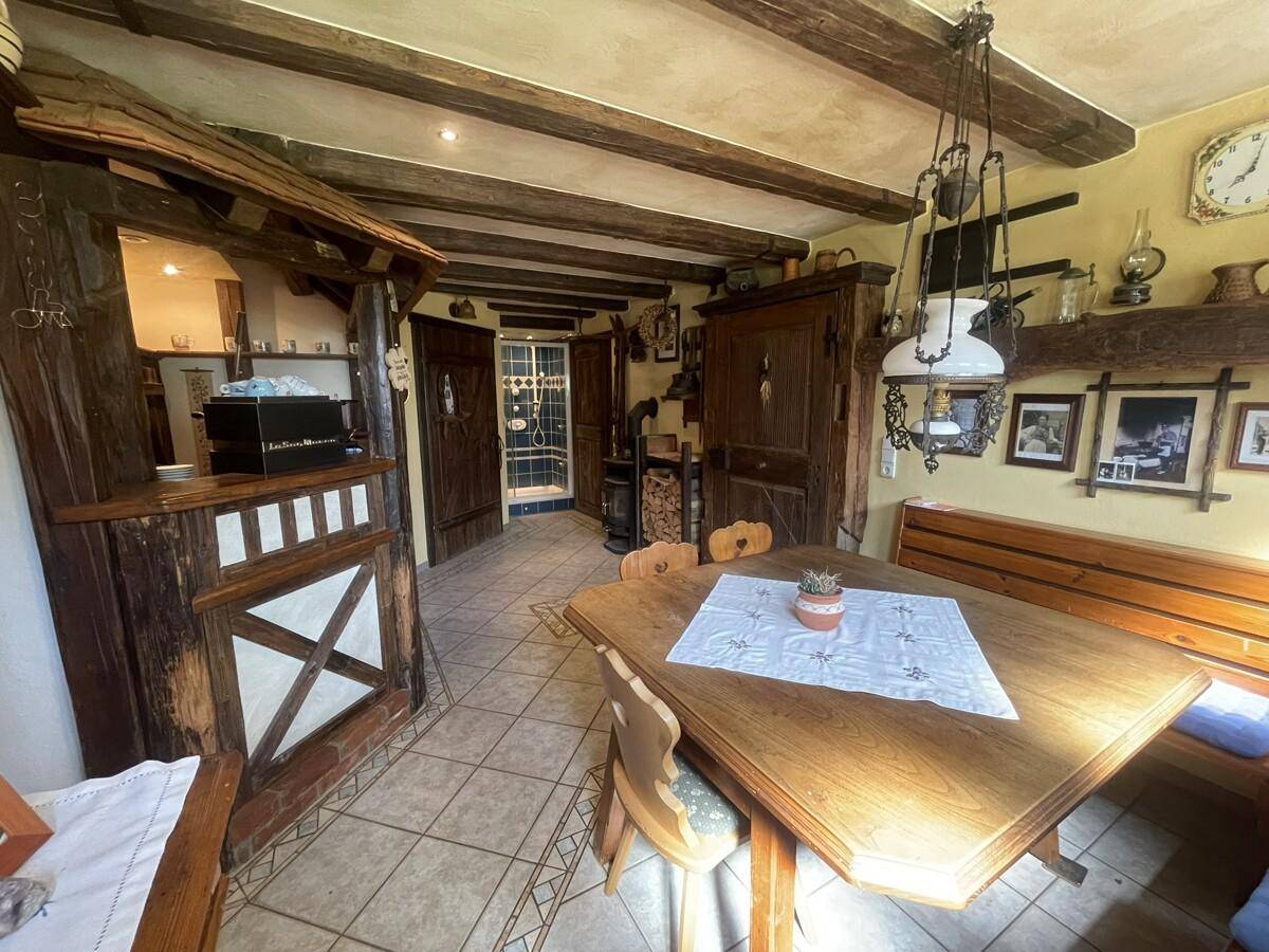 Rustikaler Wohnbereich mit Essbereich, Bar und Holzbalkendecke.