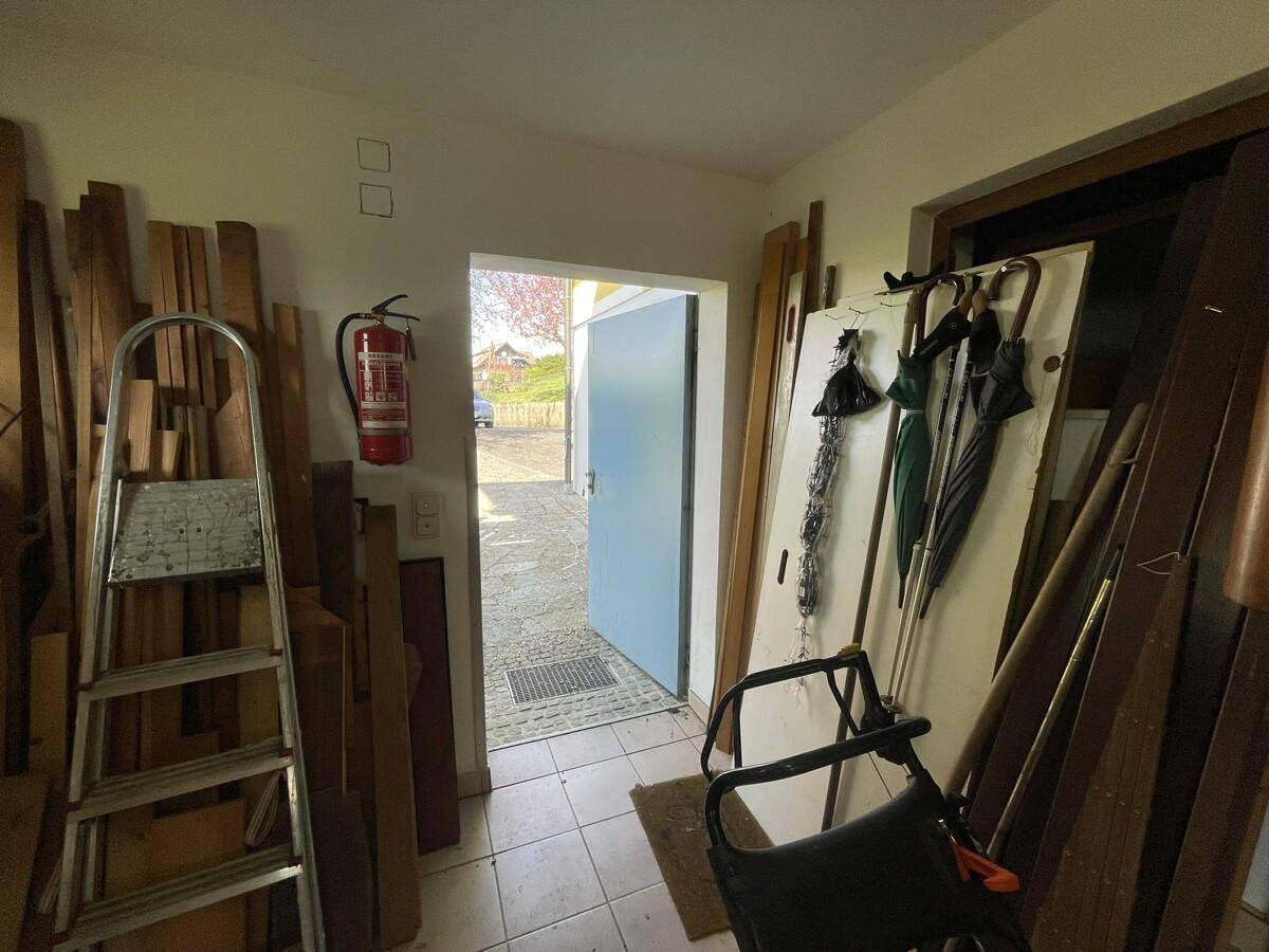 Ausgang aus der Werkstatt ins Freie, mit Leiter und Holzstapeln.