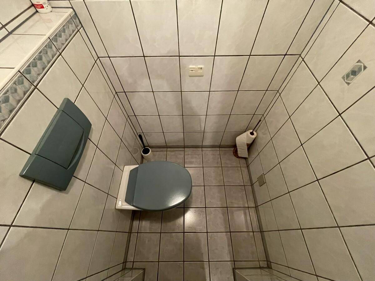 Einfaches WC mit Fliesenboden und Wand-WC.