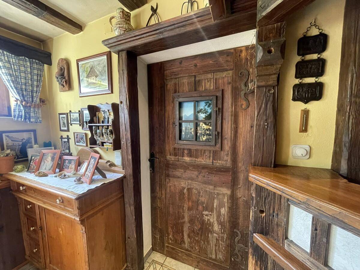 Rustikale Holztür mit kleinem Fenster und traditioneller Dekoration.