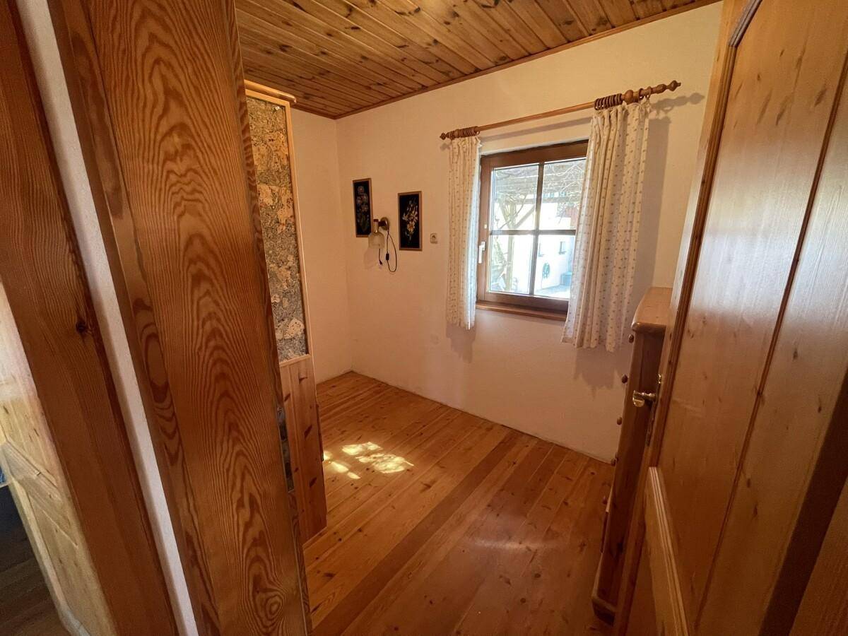 Kleines Zimmer mit Holzboden, Holzwänden und Fenster.