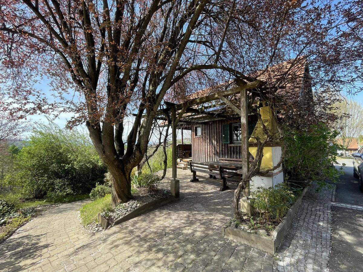 Gemütlicher Sitzbereich im Freien unter einem Baum mit Pergola.