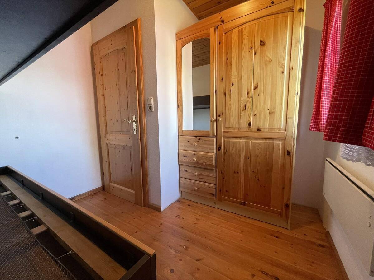 Schlafzimmer mit Holzboden, Kleiderschrank und Holztür.