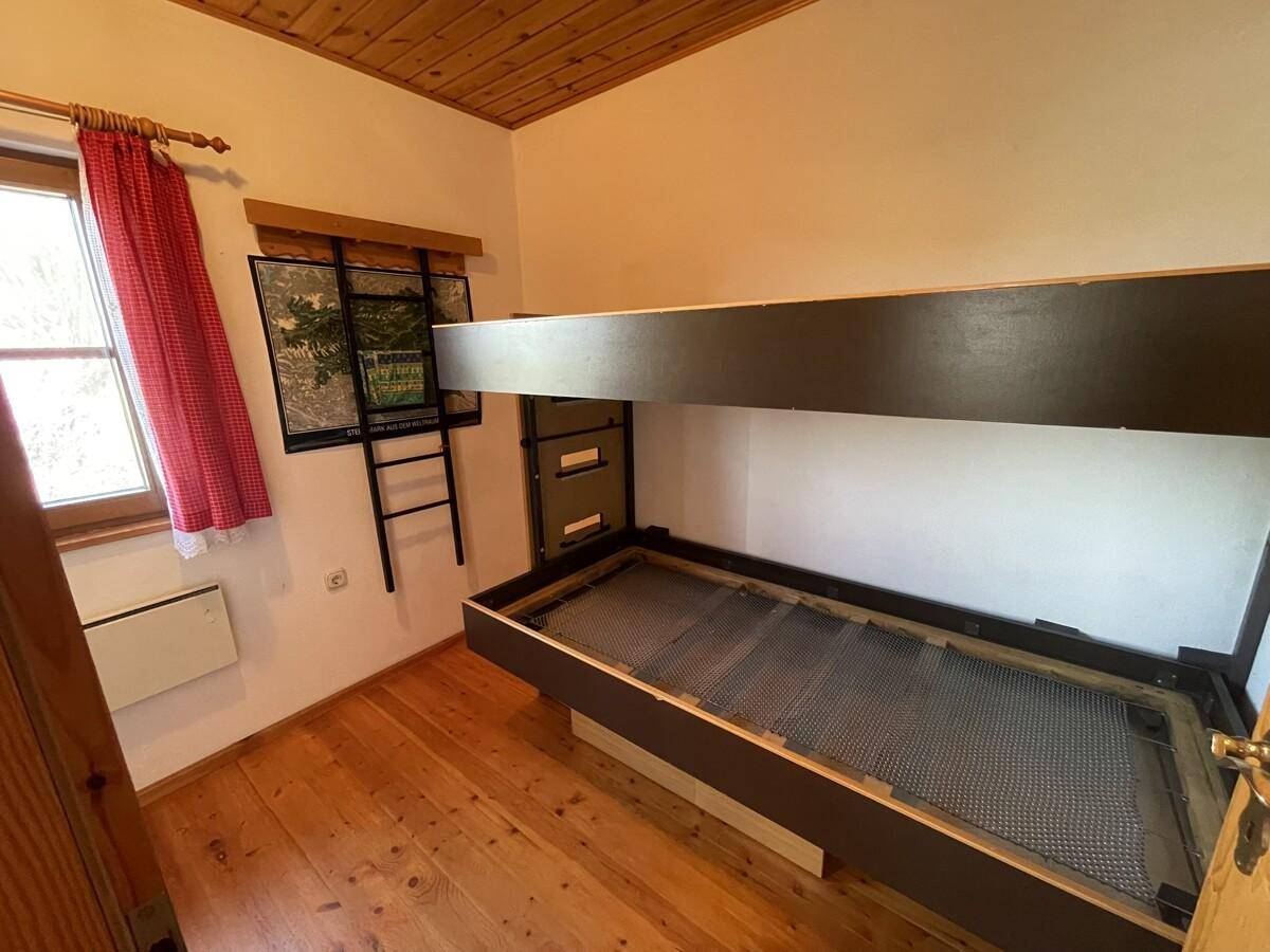 Schlafzimmer mit Etagenbett, Holzboden und Fenster.