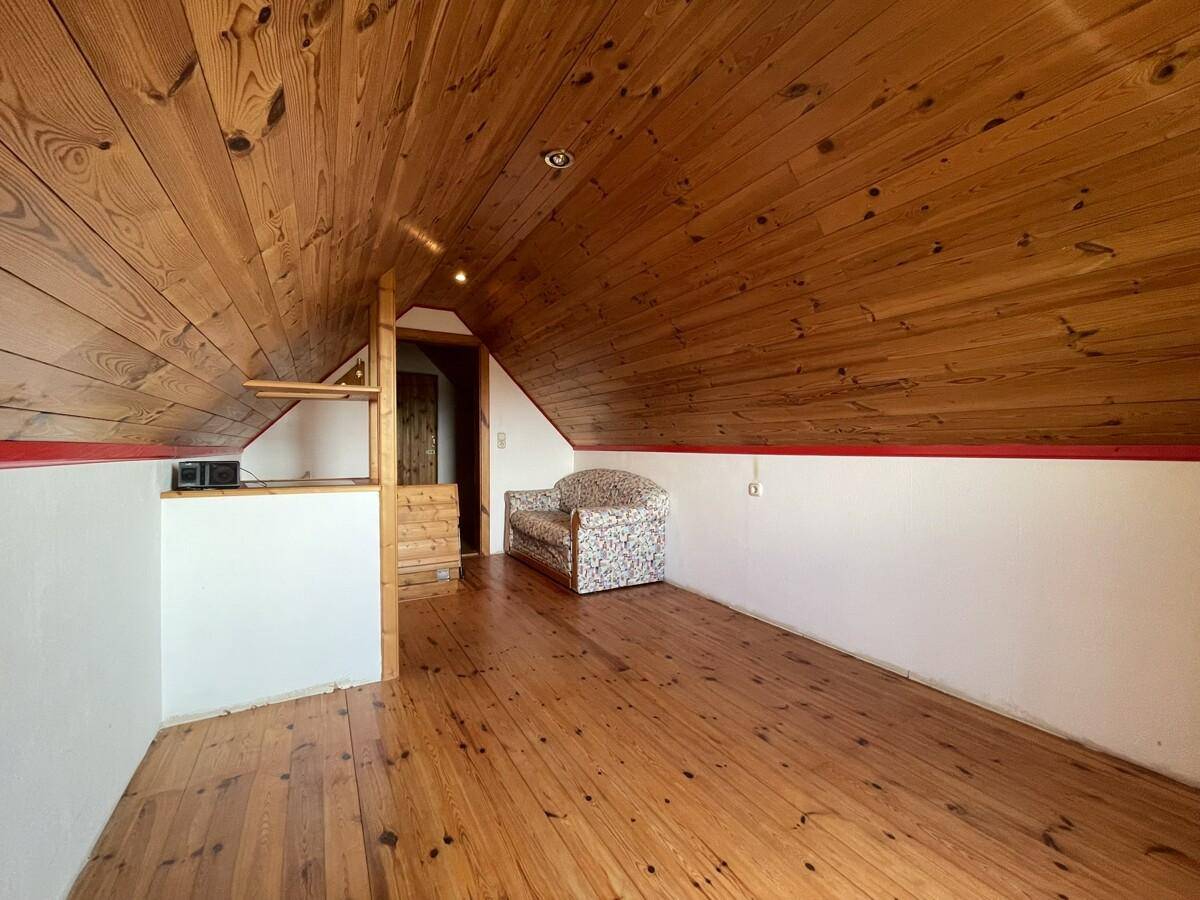 Ausgebauter Dachboden mit Holzboden, Holzdecke und gemütlicher Sitzecke.