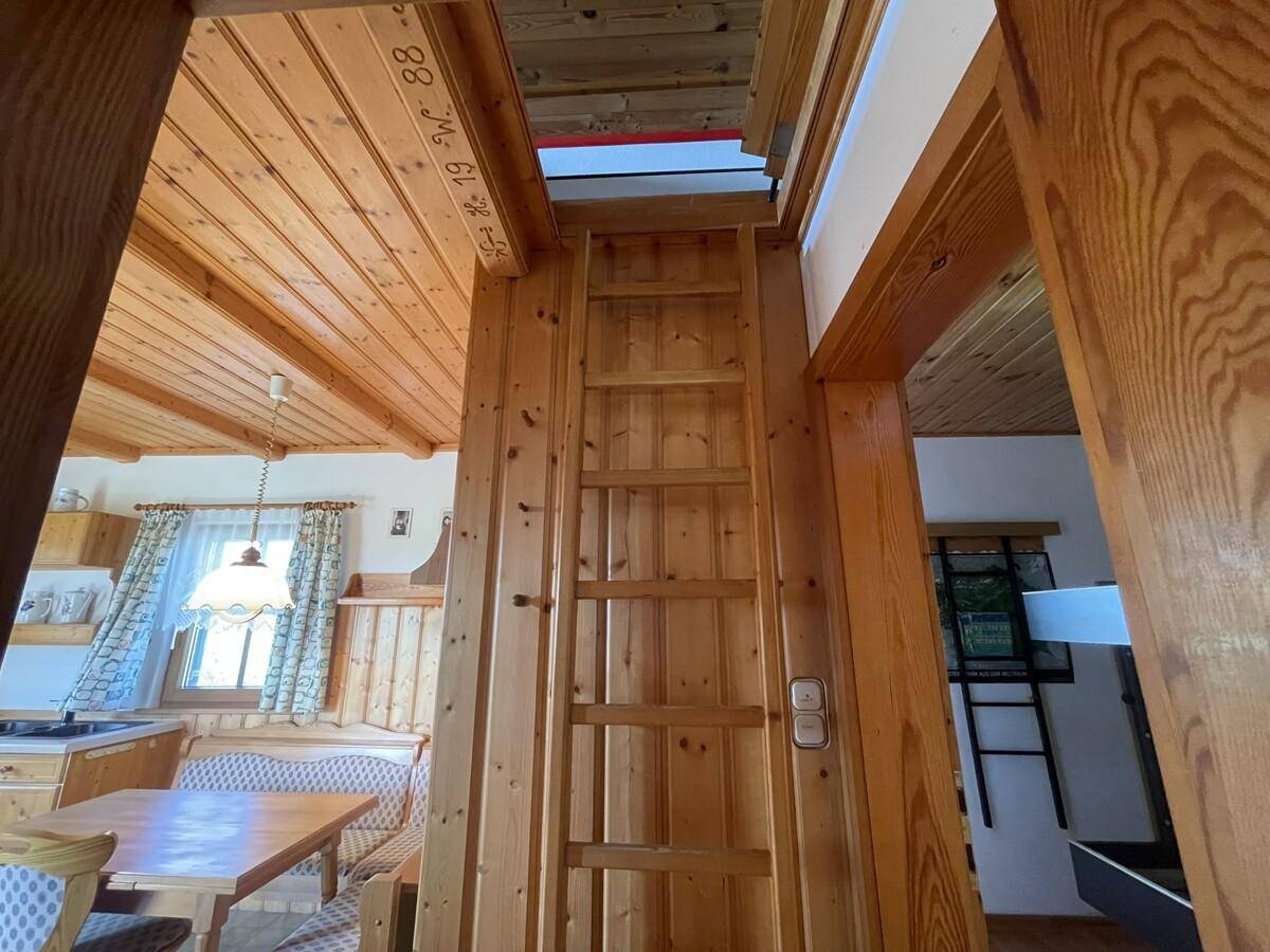 Holzleiter als Zugang zu einem oberen Bereich, mit Holzverkleidung.