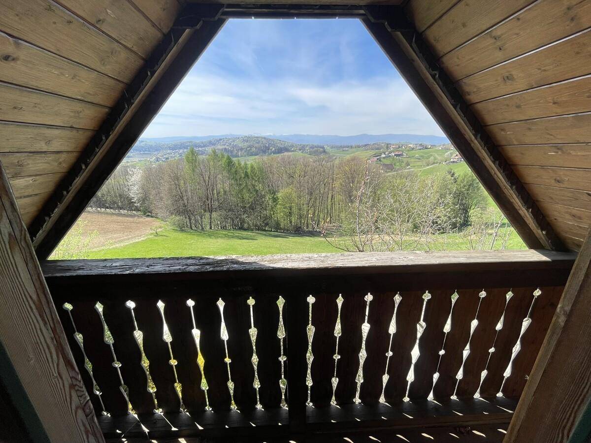 Dreieckiger Ausblick von einem Balkon auf die weite grüne Landschaft.