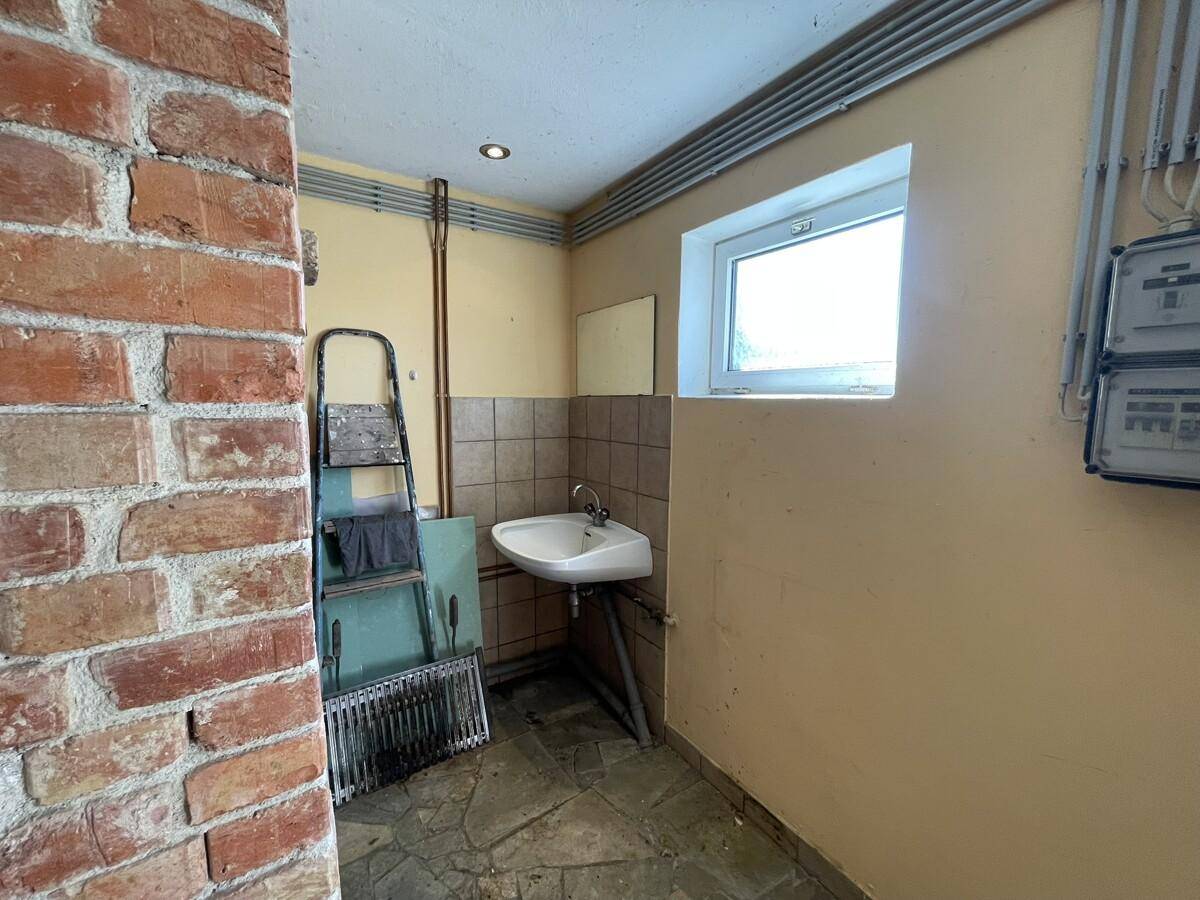 Kellerraum mit Waschbecken, Fenster und Ziegelwand.