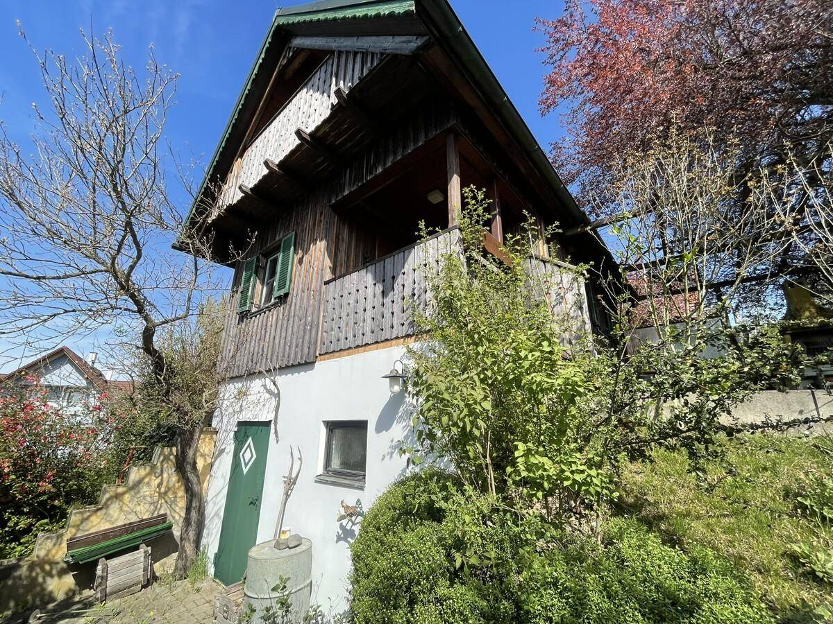 Charmantes Holzhaus mit Balkon und grüner Umgebung.