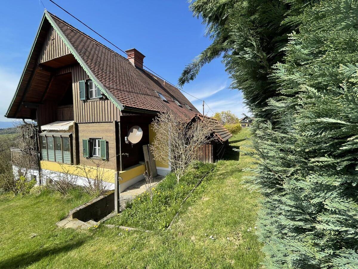 Seitenansicht des Hauses mit grünem Garten und Nebengebäude.