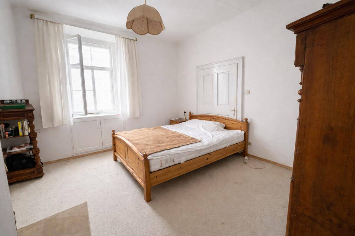 Helles Schlafzimmer mit Einzelbett, Holzmöbeln und Teppichboden.