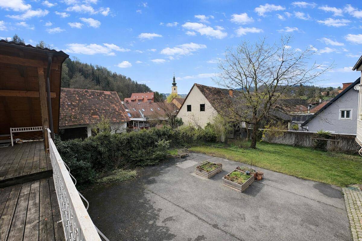 Außenbereich mit gepflastertem Hof, Rasenfläche und Blick auf die Kirche im Dorf.