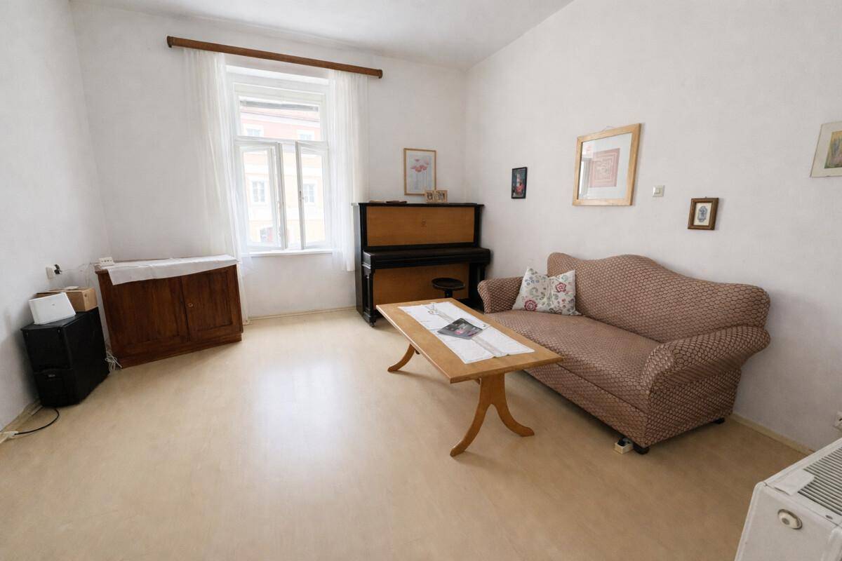 Gemütliches Wohnzimmer mit Sofa, Klavier und hellem Laminatboden.