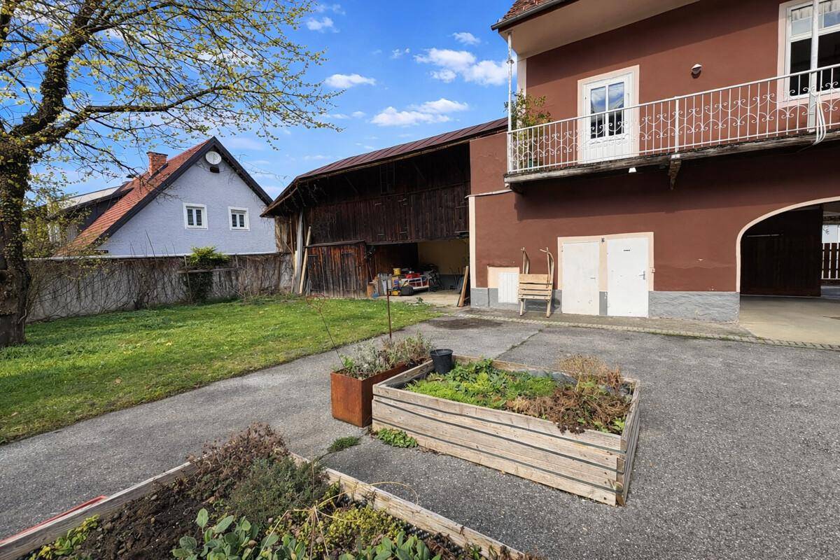 Gartenbereich mit Hochbeeten, Rasenfläche und Blick auf die umliegenden Gebäude.