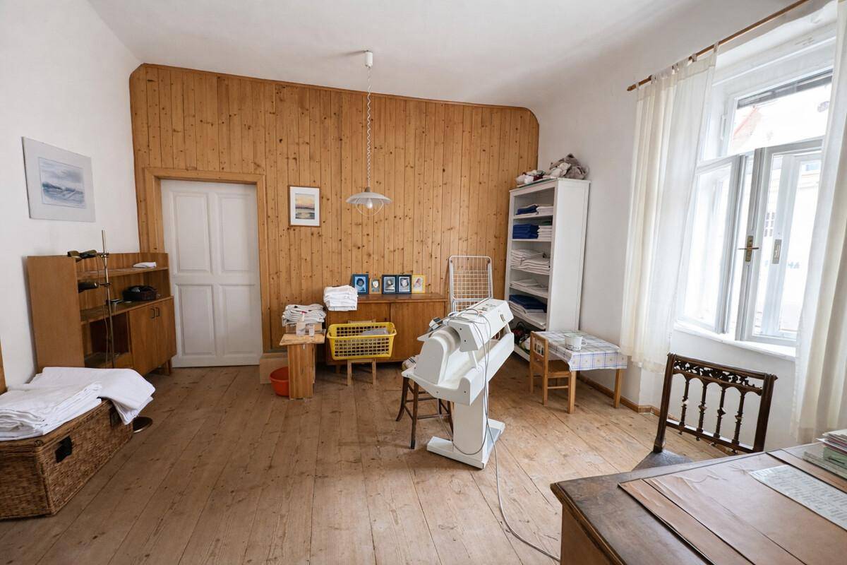 Hauswirtschaftsraum mit Holzvertäfelung, Bügelmaschine und Holzdielenboden.