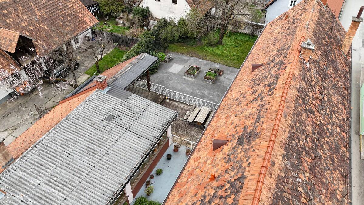 Luftaufnahme des Anwesens mit verschiedenen Dächern und einem Gartenbereich.