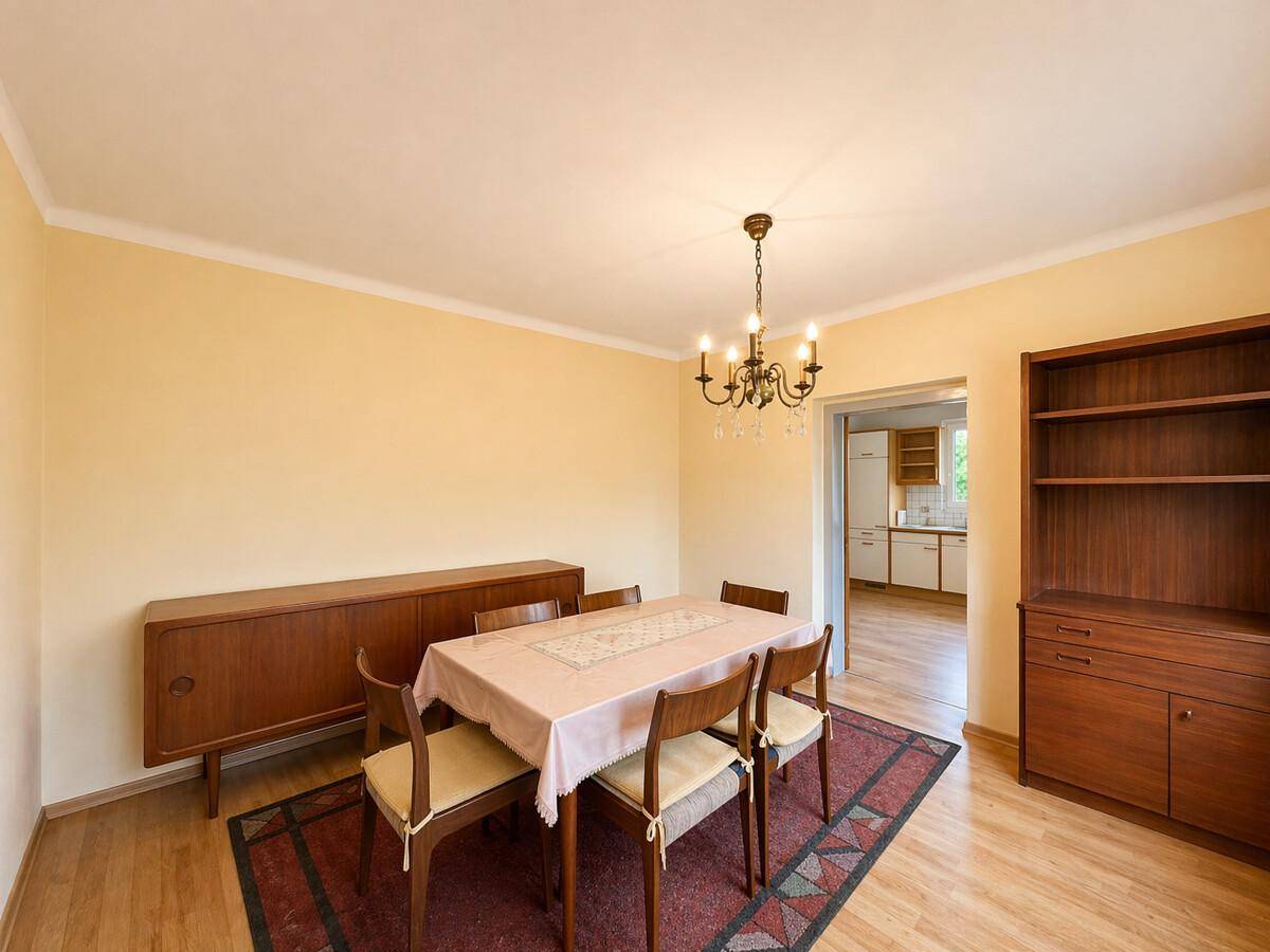 Heller Essbereich mit Holztisch, Stühlen, Sideboard und Blick in die angrenzende Küche.