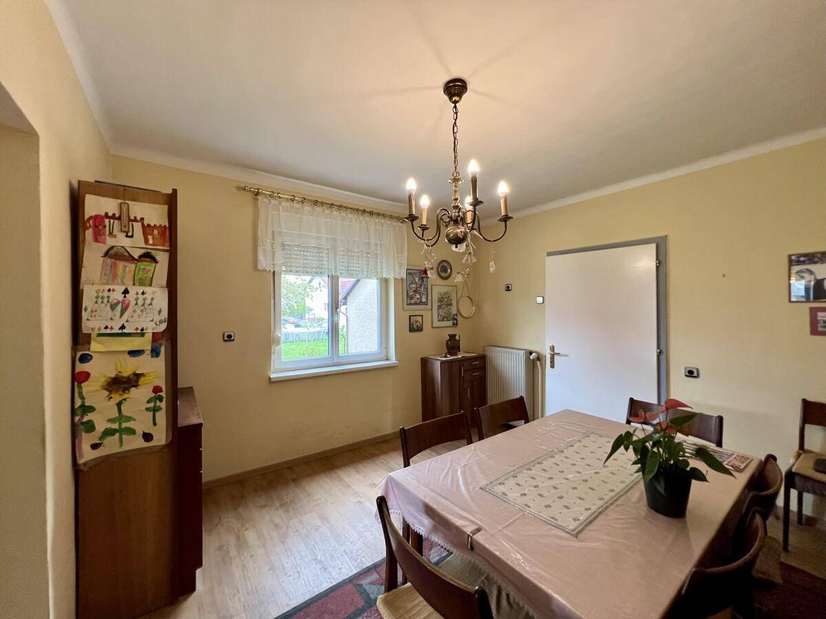 Esszimmer mit Holzboden, Fenster und traditionellem Kronleuchter, bietet Platz für gesellige Mahlzeiten.