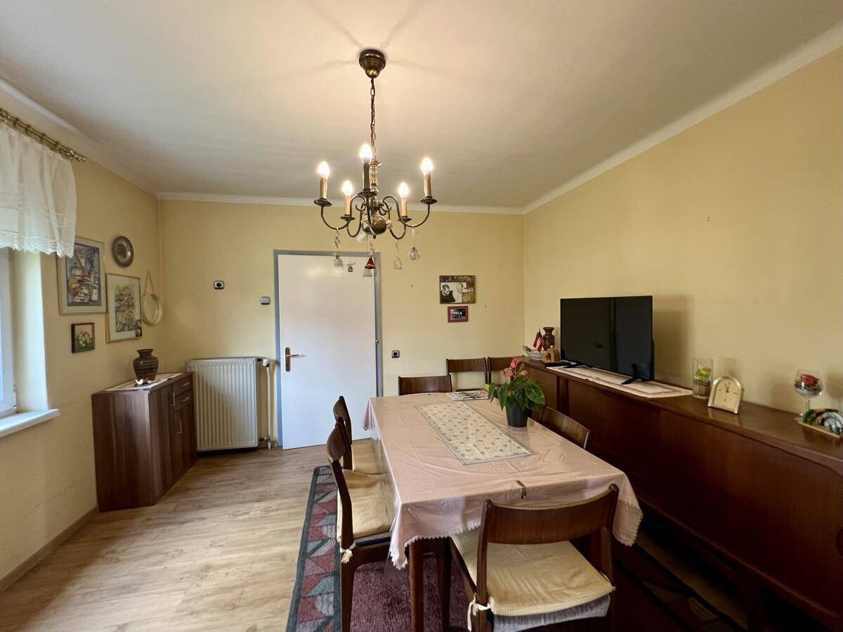 Essbereich mit Holzboden, Esstisch und Sideboard, durch eine Tür mit dem Flur verbunden.