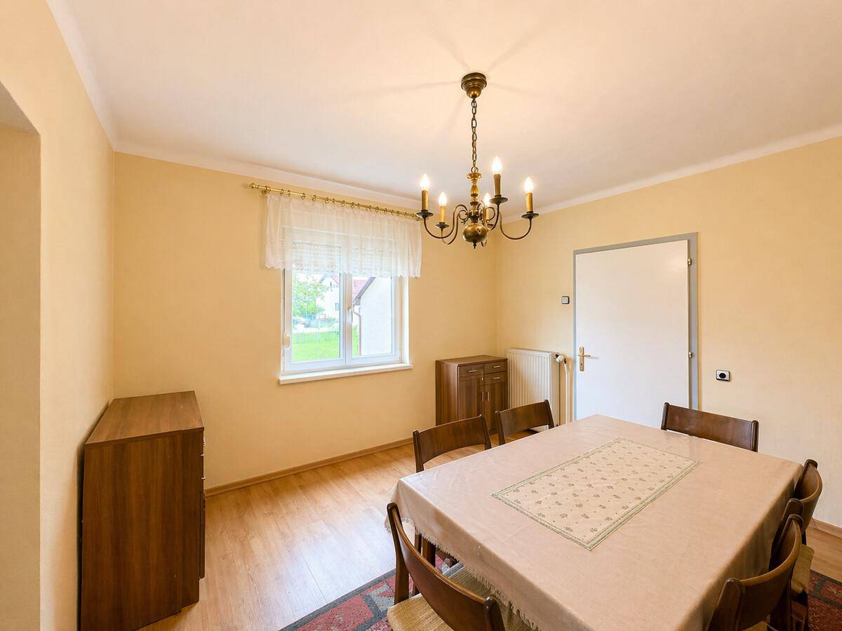 Esszimmer mit Holzboden, Fenster und traditionellem Kronleuchter, ideal für Familienessen.