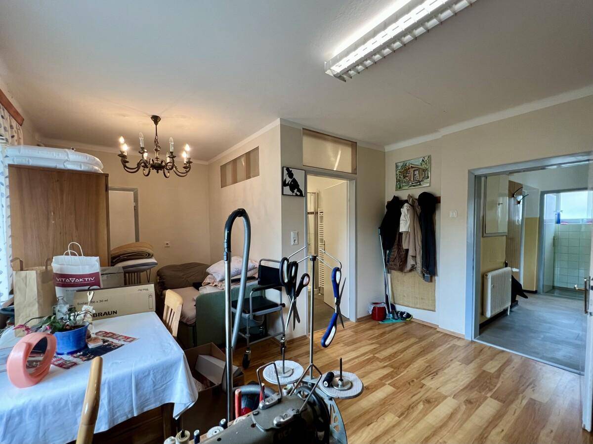 Geräumiger Raum mit Laminatboden, Fenster und Zugang zu einem Badezimmer und Flur.