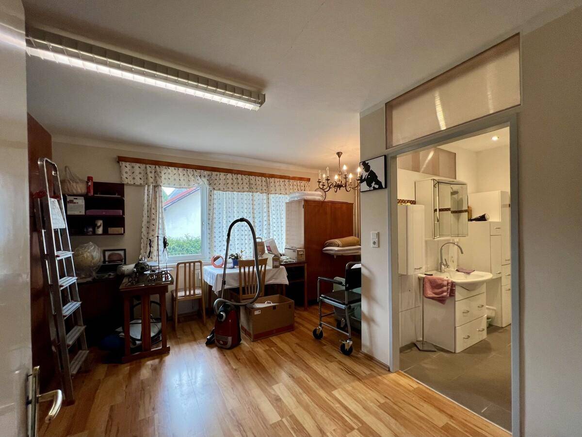 Vielseitiger Raum mit Laminatboden, Fenster und offenem Zugang zu einem Badezimmer.