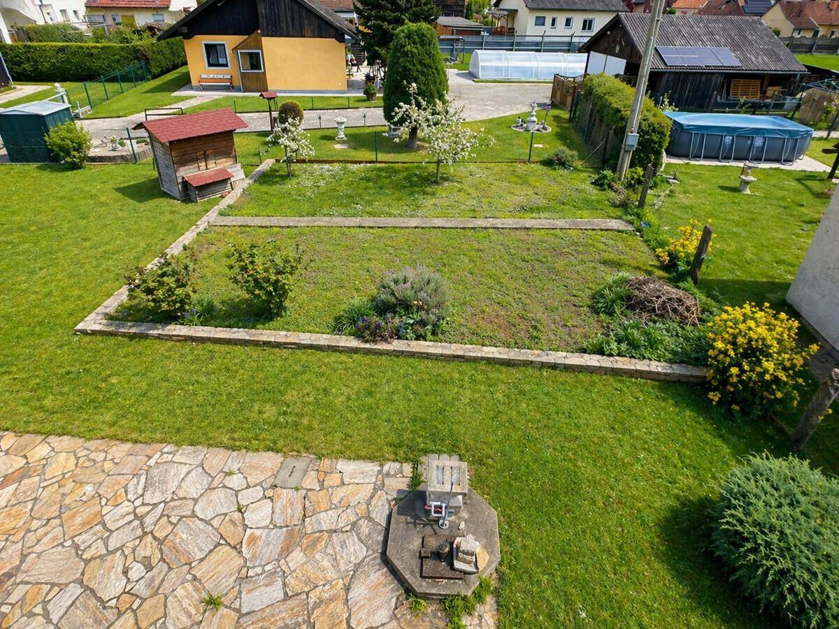 Weitläufiger Gartenbereich mit Rasenflächen, Beeten, einem kleinen Pool und einem Gartenhaus.