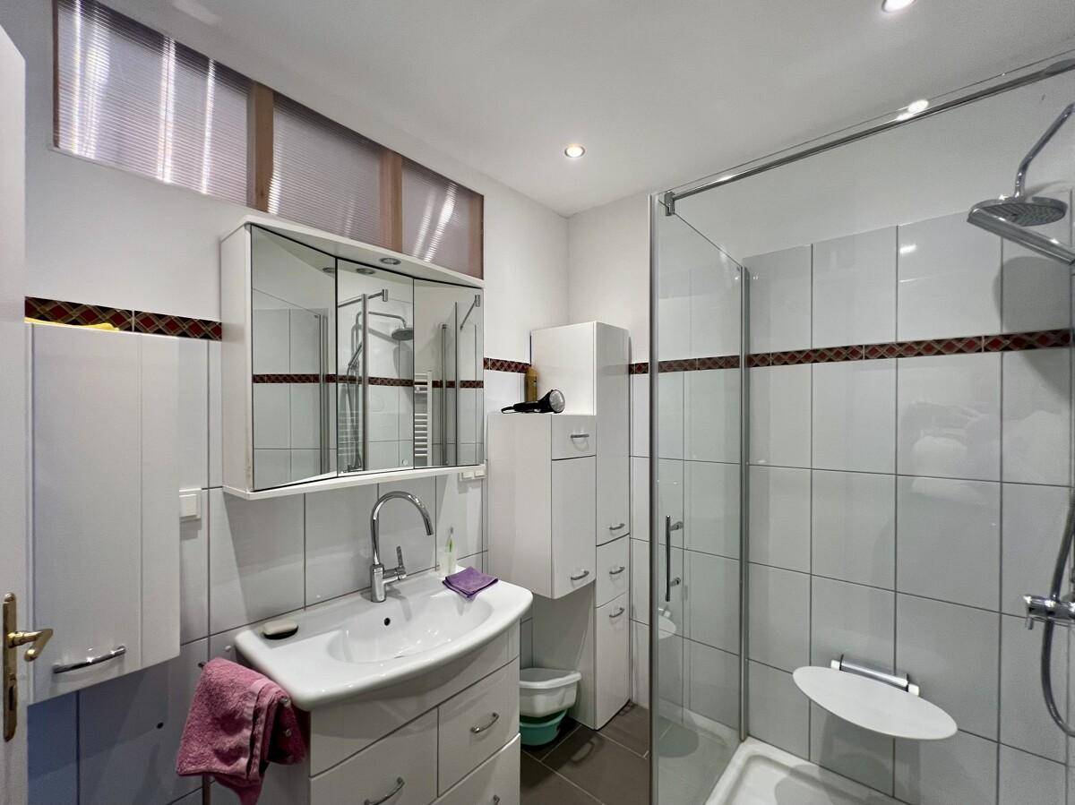 Modernisiertes Badezimmer mit Duschkabine, Waschbecken und Spiegelschrank, funktional und hell.