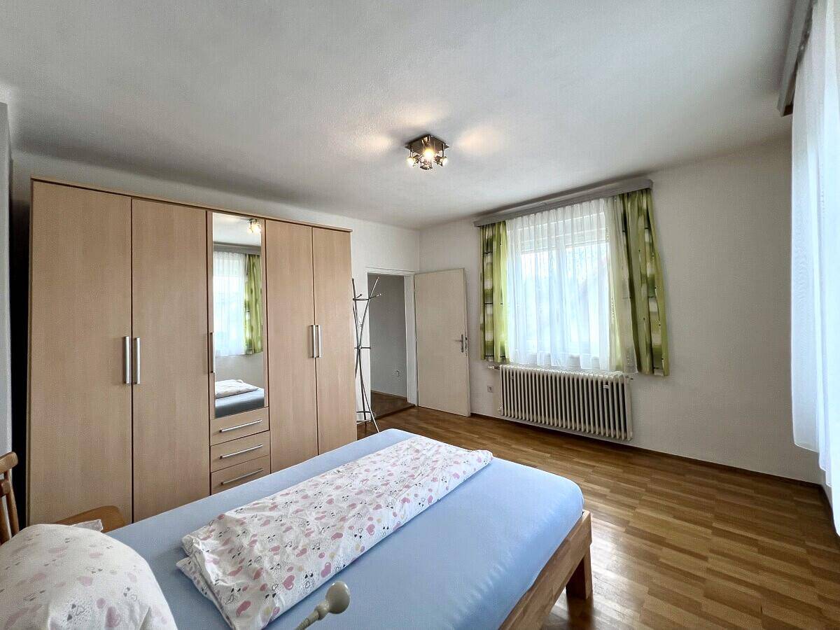 Schlafzimmer mit Parkettboden, großem Kleiderschrank und Fenster, das viel Tageslicht bietet.