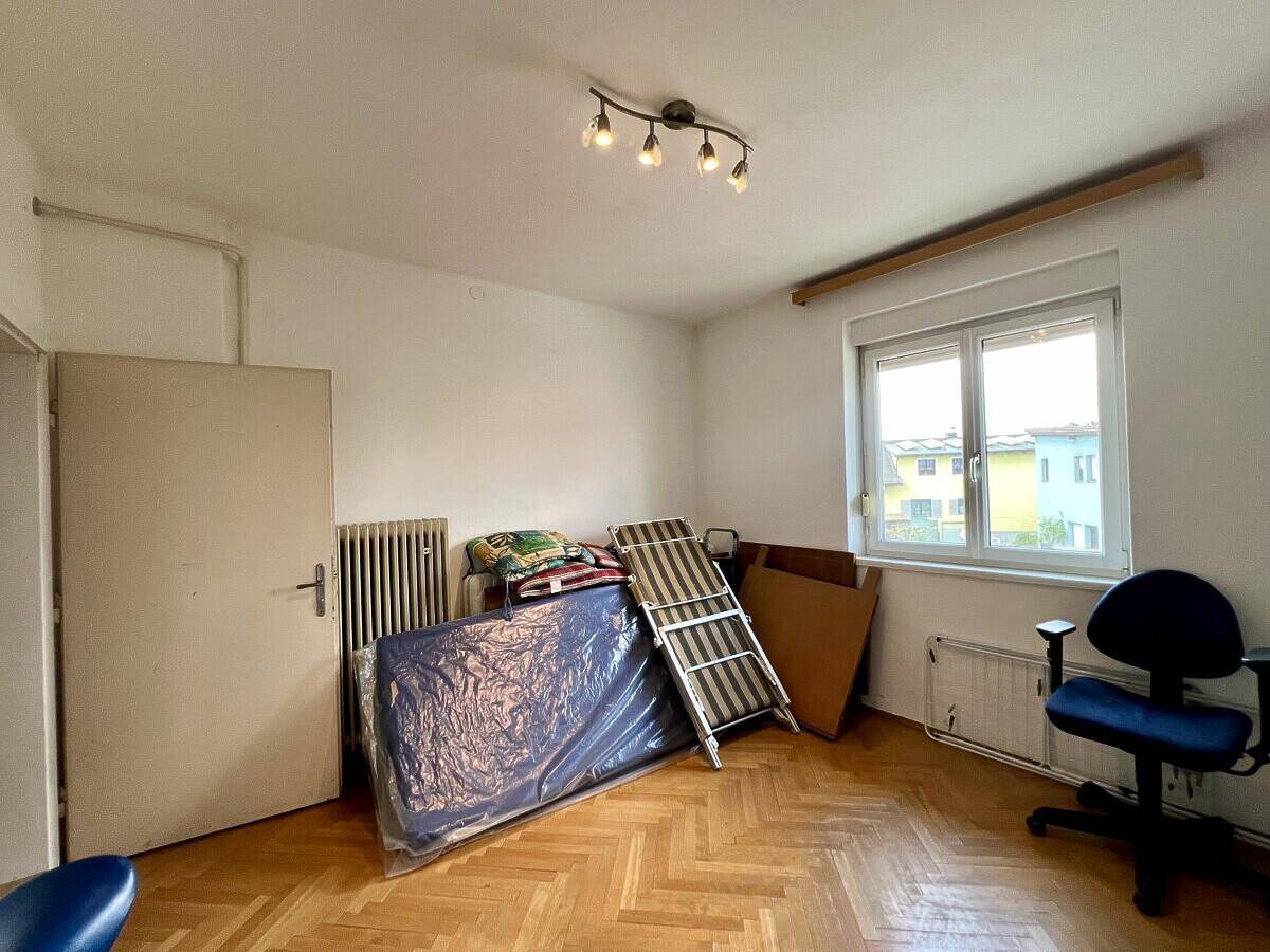 Schlafzimmer mit Parkettboden, Fenster und Heizkörper, bietet Raum für persönliche Gestaltung.