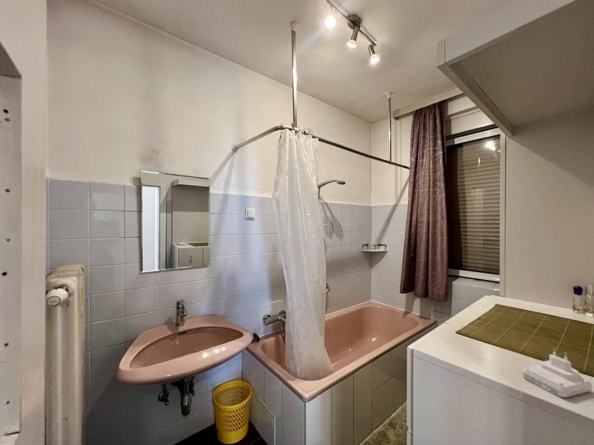 Badezimmer im 80er-Jahre-Stil mit rosa Badewanne, Waschbecken und Fliesen an den Wänden.