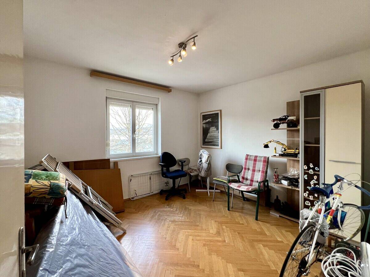 Geräumiges Schlafzimmer mit Parkettboden, Fenster und viel Platz für individuelle Einrichtung.