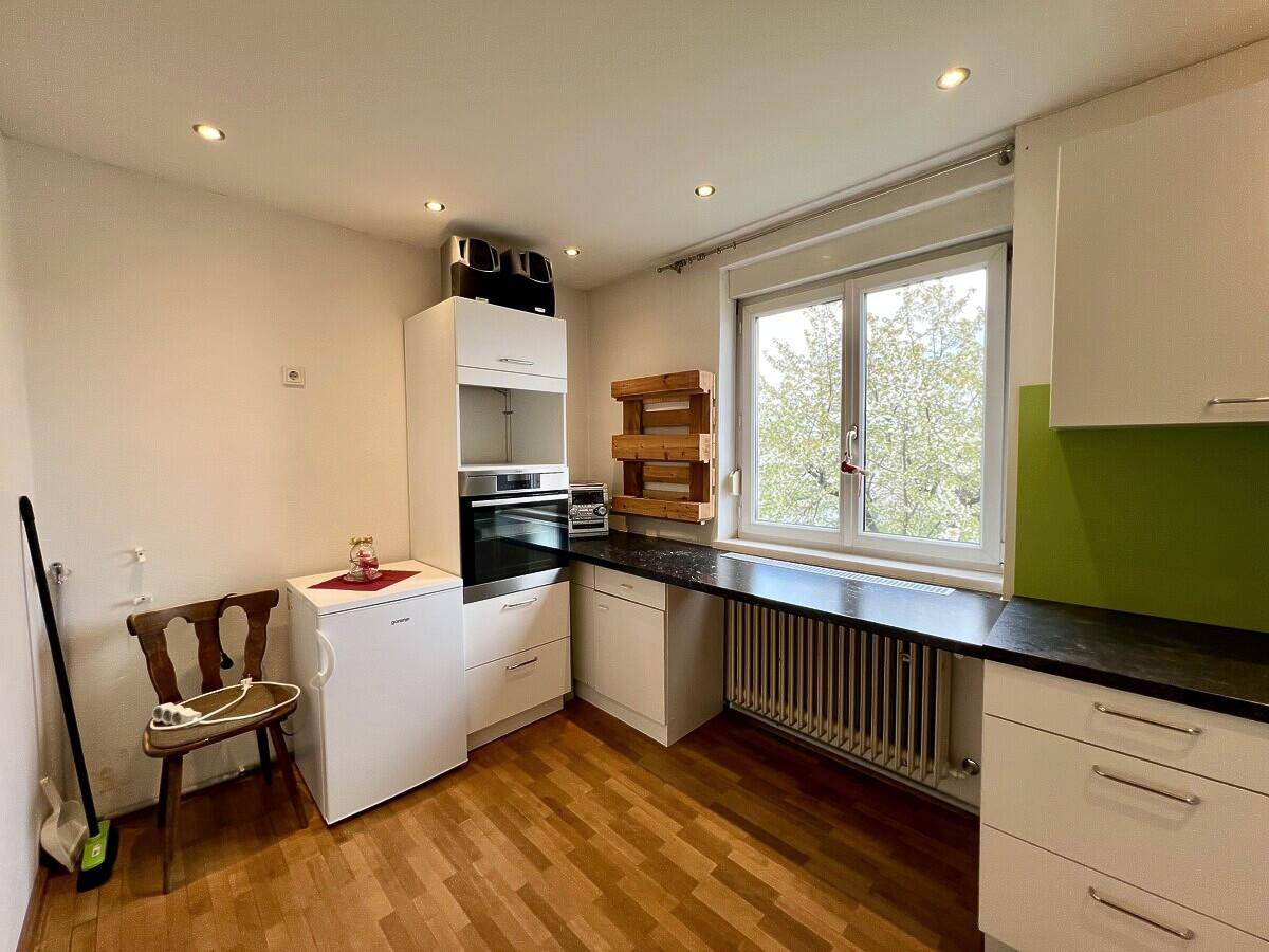 Funktionale Küchenzeile mit weißen Schränken, integriertem Backofen und Fenster.