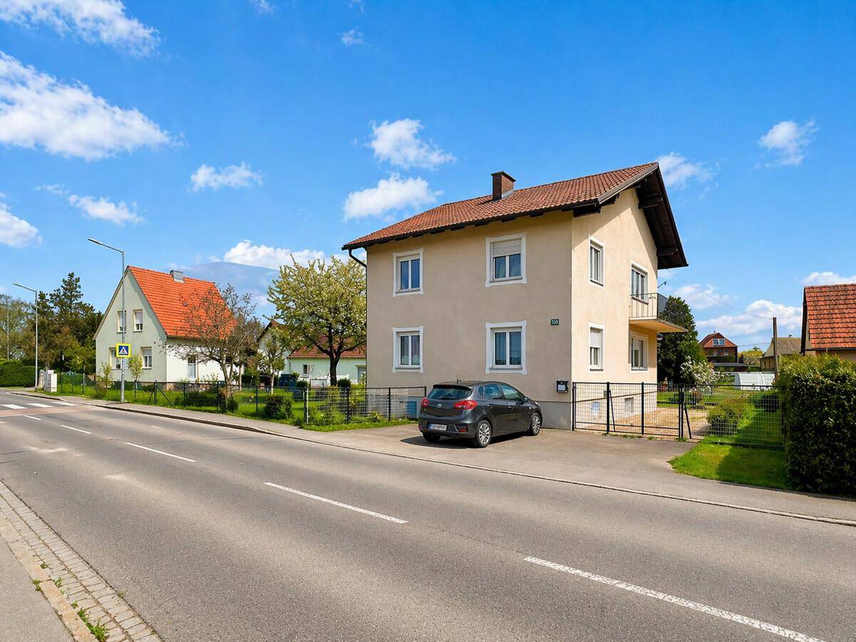 Ansicht des Hauses von der Straße aus mit Vorgarten und geparktem Auto.