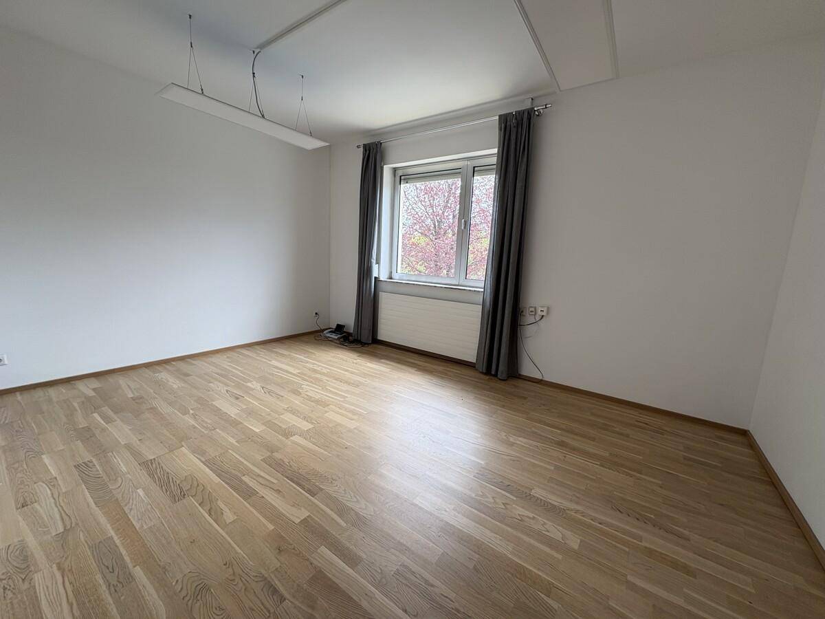 Heller Raum mit Holzboden und großem Fenster, ideal als Büro oder Arbeitszimmer.