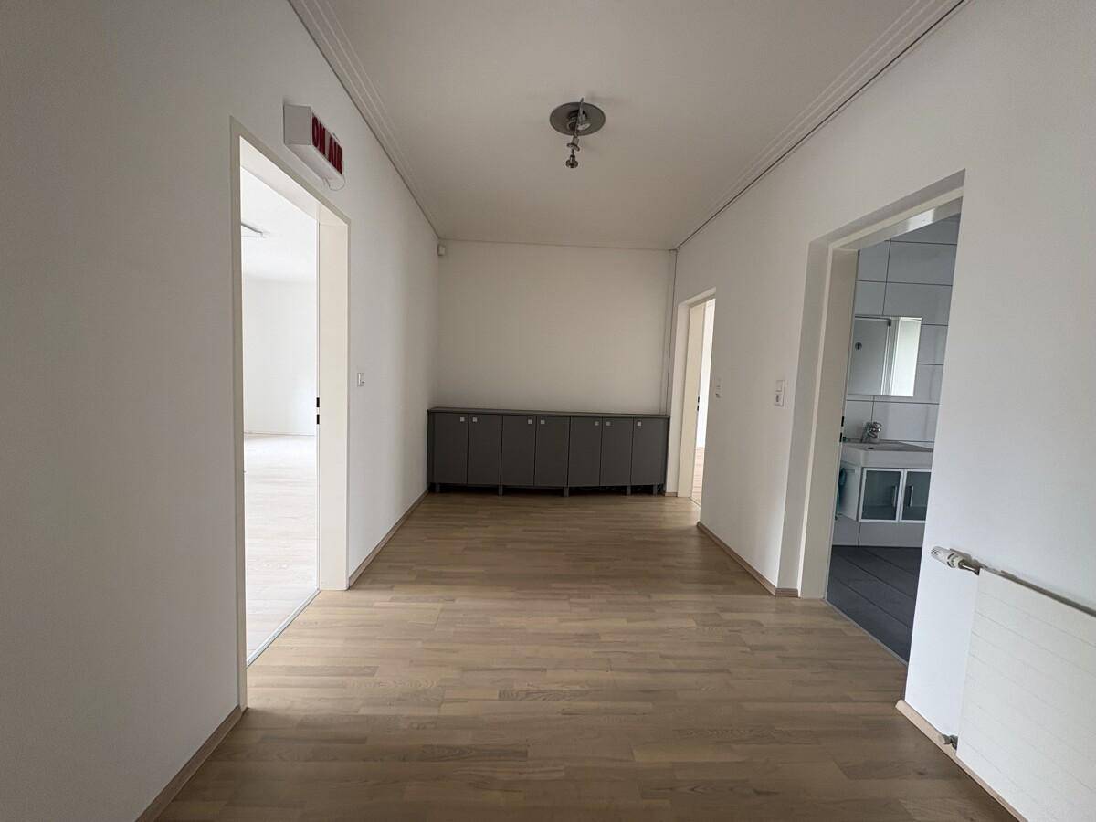 Langer Flur mit Holzboden, der zu verschiedenen Räumen und einem Badezimmer führt.