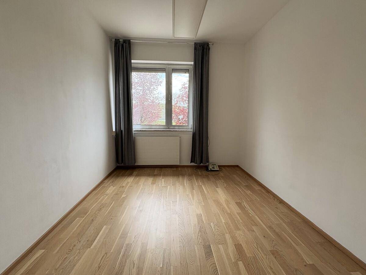 Kleinerer Raum mit Holzboden und einem Fenster, geeignet als Einzelbüro.