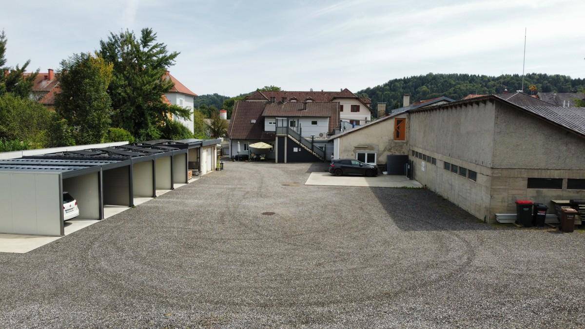 Weitläufiger Schotterparkplatz mit Carports und Blick auf die umliegende Hügellandschaft.