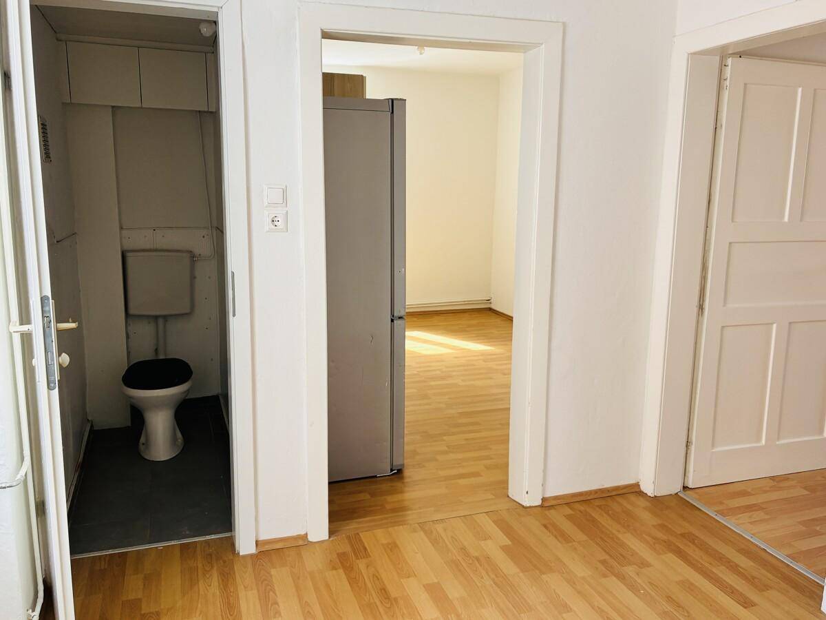 Heller Flurbereich mit Holzfußboden und Zugang zu einer separaten Toilette und einem weiteren Zimmer.