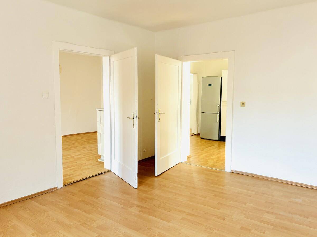Zentraler Raum mit hellem Parkettboden und mehreren Türen, die zu anderen Zimmern führen.