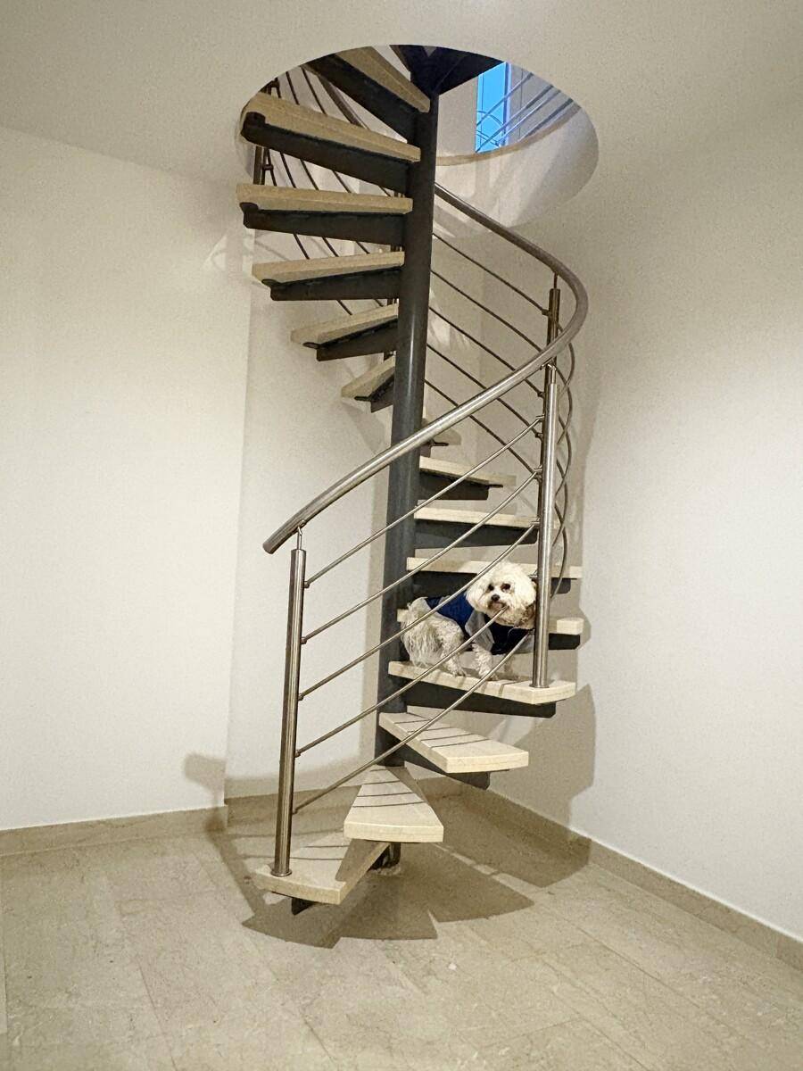Elegante Wendeltreppe aus Metall und Holz, die die verschiedenen Ebenen des Hauses verbindet.