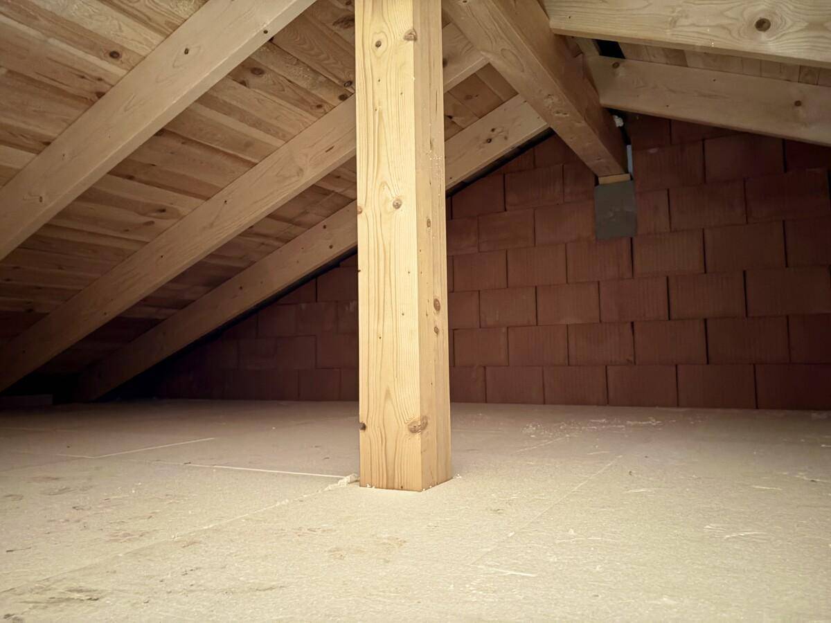 Geräumiger Dachboden mit sichtbaren Holzbalken und Stützpfeiler, ideal für zukünftigen Ausbau.