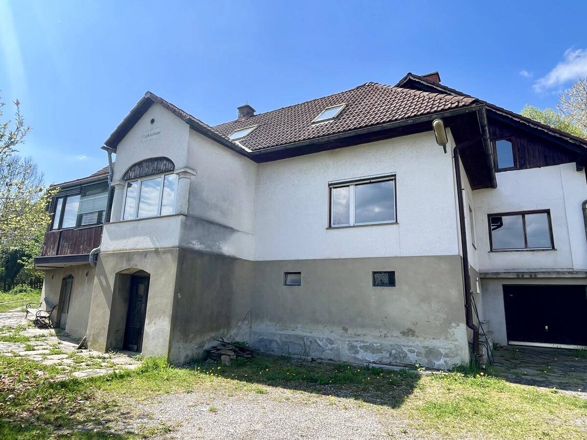 Seitenansicht des Hauses mit verschiedenen Fassadenbereichen, einem Erker und einer Garageneinfahrt.