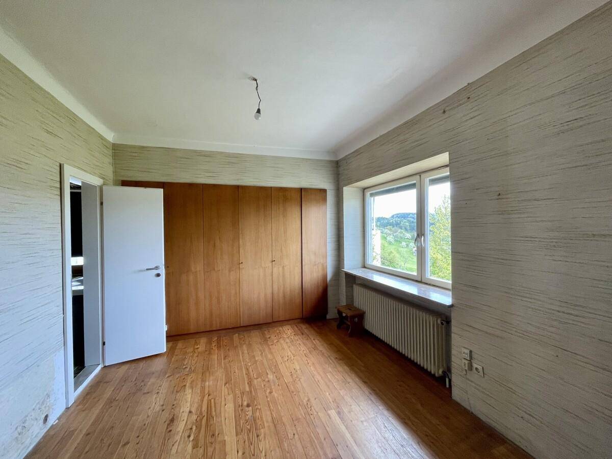 Schlafzimmer mit Holzboden, strukturierten Tapeten und einem großen Einbauschrank entlang einer Wand.