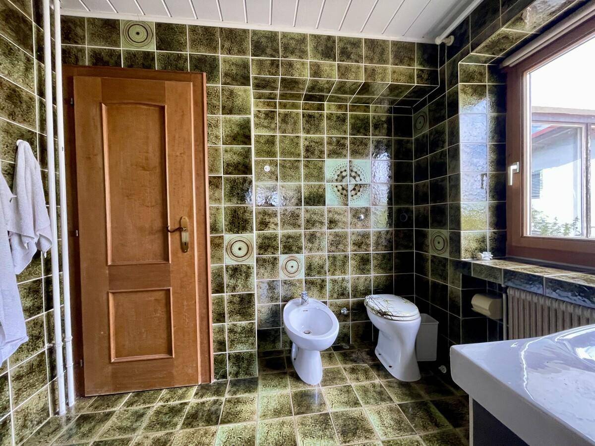 Badezimmer mit auffälligen grünen Fliesen, Bidet, Toilette und Fenster.