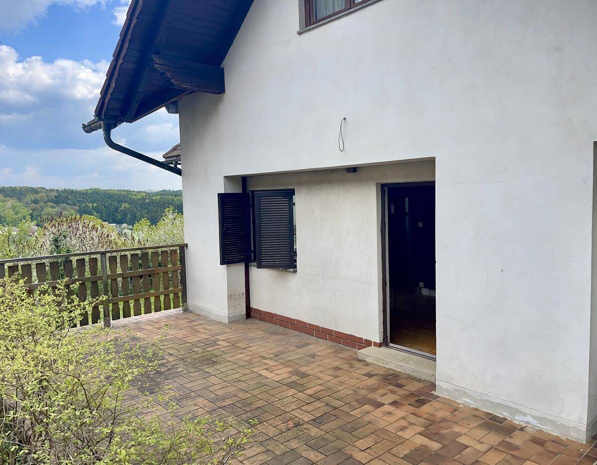 Große Terrasse mit Ziegelpflaster und weitem Blick über die grüne Landschaft.