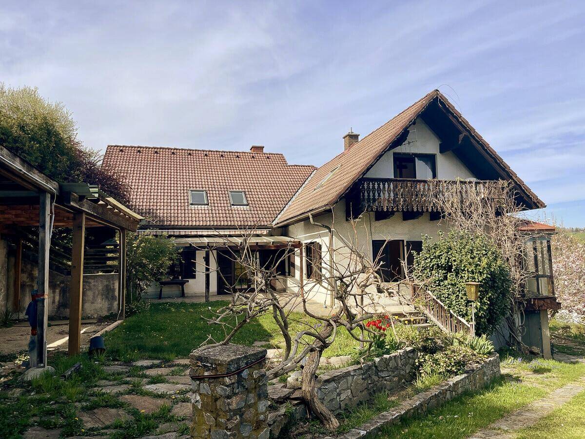 Charmantes Haus mit Garten, mehreren Dächern und einem kleinen Balkon.