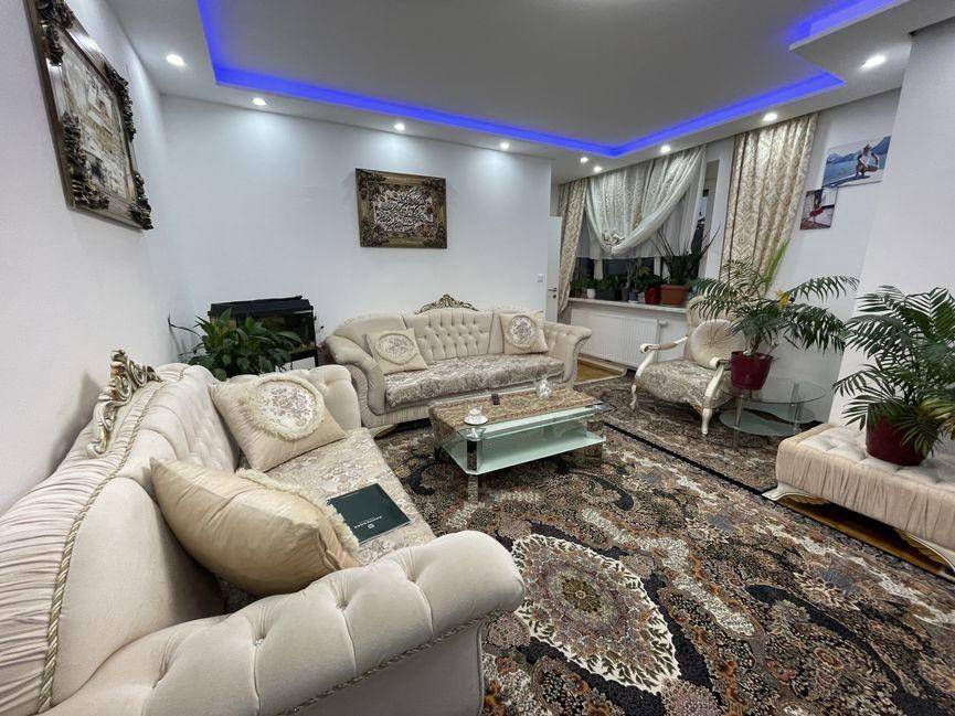 Gemütliches Wohnzimmer mit opulenten Sofas, einem großen Teppich und indirekter Deckenbeleuchtung.